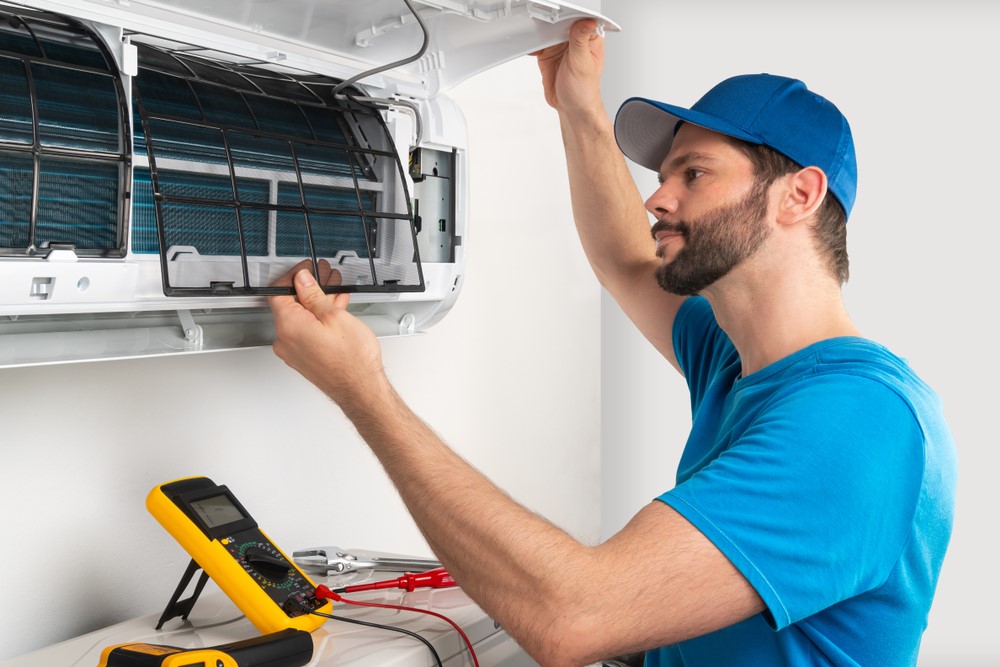 HVAC-Pro Technician Servicing a Mini Split AC Unit in a Blue Shirt and Blue Hat